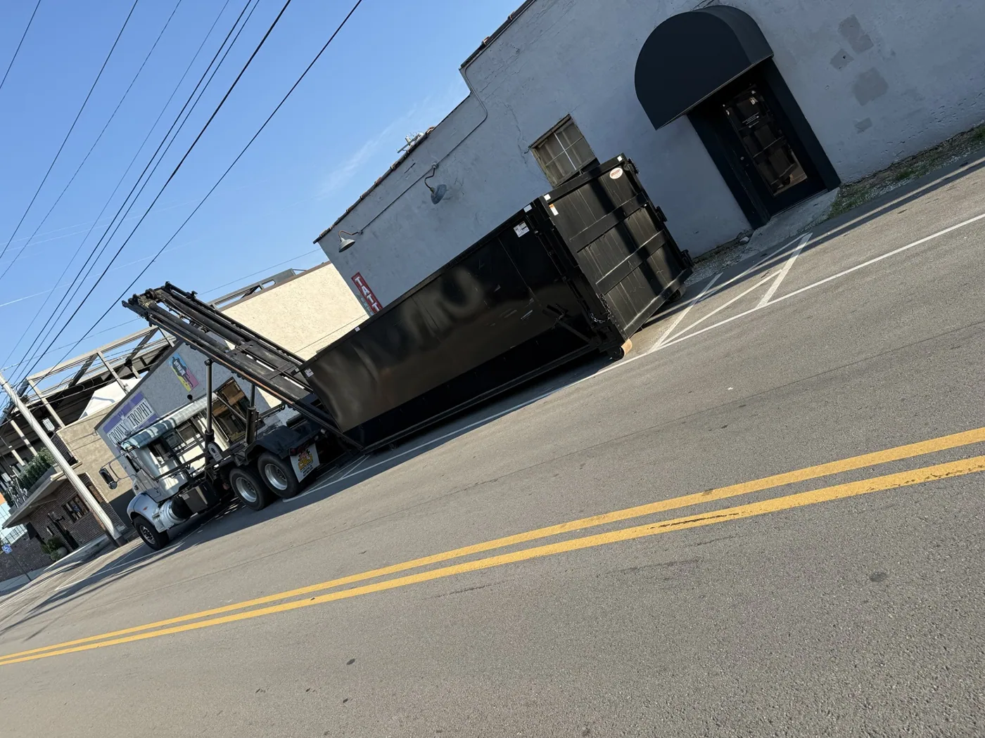 Black roll-off dumpster positioned roadside
